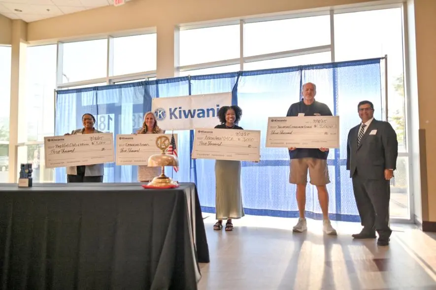 Group of individuals holding large checks as recipients of a Kiwanis grant